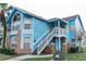 Light blue two-story condo building with brick accents and a stairway at 2741 N Poinciana Blvd # 43, Kissimmee, FL 34746