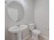 Clean half bathroom with pedestal sink, round mirror, and modern fixtures at 306 Hang Loose Way, Daytona Beach, FL 32124
