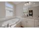Bright bathroom featuring a large soaking tub, granite counters, and white cabinetry at 306 Hang Loose Way, Daytona Beach, FL 32124