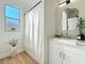 Bright bathroom featuring a modern vanity with gold accents, decorative mirror and a window over the tub at 3841 Golden Knot Dr, Kissimmee, FL 34746
