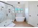 Modern bathroom with a walk-in glass shower, a soaking tub, and double windows at 3841 Golden Knot Dr, Kissimmee, FL 34746