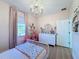 Pink themed bedroom featuring a charming chandelier, a white dresser and a window at 3841 Golden Knot Dr, Kissimmee, FL 34746