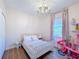 Pink themed bedroom featuring a charming chandelier, a white bed frame and a window at 3841 Golden Knot Dr, Kissimmee, FL 34746