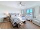 Sunlit main bedroom featuring a tufted headboard bed, a bench, a crib, and hardwood floors at 3841 Golden Knot Dr, Kissimmee, FL 34746