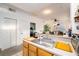 Open kitchen with stainless steel sink, wooden cabinets, and views into the living room and Primary bedroom at 4000 San Gallo Dr # 102, Kissimmee, FL 34741
