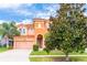 Two-story house with orange stucco and tile roof, lush landscaping, and a magnolia tree at 4525 Stella St, Kissimmee, FL 34746