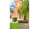 Two-story house with orange exterior, lush landscaping, and palm trees at 4525 Stella St, Kissimmee, FL 34746