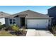 Exterior view of a single story house with a white garage door and landscaping at 522 Noble Ave, Davenport, FL 33837