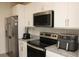 Modern kitchen featuring stainless steel appliances, granite countertops, and white cabinets, perfect for cooking at 697 Stoney Point Cir, Davenport, FL 33896