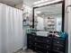Bathroom with a large black vanity, vessel sink, glass shelves, and a shower with a white curtain at 123 Lakeview Dr, Auburndale, FL 33823