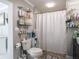 Cozy bathroom featuring a toilet, shower with white curtain, and open shelving with toiletries at 123 Lakeview Dr, Auburndale, FL 33823