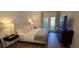 Well-lit main bedroom showcases hardwood floors, a plush bed, a modern dresser, and doors to a private balcony at 14214 Fredricksburg Dr # 106, Orlando, FL 32837