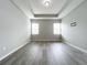 Bright bedroom features two windows, tray ceiling, and gray wood-look flooring, creating a modern and airy atmosphere at 2559 Sedge Grass Way, Orlando, FL 32824