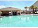 Sparkling community pool with lounge chairs and covered seating area under a bright blue sky at 2559 Sedge Grass Way, Orlando, FL 32824