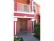 Coral townhome featuring a brown entry door, white trim, and a small front porch at 261 Autumn Ln # 4, Kissimmee, FL 34743