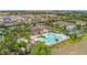 Stunning aerial view of the community pool, showcasing lush landscaping, a clubhouse, and ample lounge space at 2833 Oakwater Dr # 169, Kissimmee, FL 34747