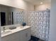 Bright bathroom features double sinks, a shower with flower curtain, and a large mirror at 401 Chayne Pl, St Cloud, FL 34771