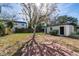 A large tree casts shadows on a backyard with a brick patio, adjacent to a shed at 5438 San Luis Dr, Orlando, FL 32807