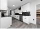 Modern kitchen featuring white cabinets, black hardware and countertops, stainless steel appliances, and gray floors at 5438 San Luis Dr, Orlando, FL 32807