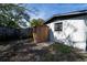 A wooden shed with a door and window sits on a grassy patch next to the white building at 5438 San Luis Dr, Orlando, FL 32807