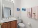Cozy half bathroom featuring a vanity with sink, toilet, and decorative flamingo-themed towels at 663 Shorehaven Dr, Poinciana, FL 34759