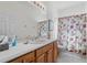 Well-lit bathroom with a wooden vanity, large mirror, and shower with floral curtain at 663 Shorehaven Dr, Poinciana, FL 34759