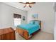 Cozy bedroom features a blue quilted bedspread, wooden furniture, and a ceiling fan at 663 Shorehaven Dr, Poinciana, FL 34759