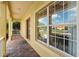 Covered front porch with brick flooring, white railing, and a view of the landscaped front yard at 663 Shorehaven Dr, Poinciana, FL 34759
