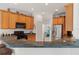 Open kitchen featuring wood cabinets, black appliances, a gray countertop, and a stainless steel refrigerator at 663 Shorehaven Dr, Poinciana, FL 34759