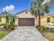 Single-story home with a brown garage door and landscaped front yard at 669 Grand Canal Dr, Kissimmee, FL 34759