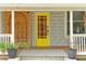 Welcoming front porch featuring a bright yellow door, decorative accents, and potted plants enhancing curb appeal at 723 New York Ave, St Cloud, FL 34769