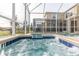Relaxing hot tub with cascading water feature, screened enclosure, and pool in the background at 771 Drop Shot Dr, Davenport, FL 33896