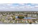 Wide aerial view of the home with a large pond, lush trees, and surrounding neighborhood at 83 Alameda Dr, Kissimmee, FL 34743