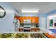 Bright kitchen with orange cabinets, stainless steel appliances, tile backsplash, and an adjacent breakfast bar at 2203 Key West Ct # 435, Kissimmee, FL 34741
