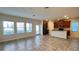 Open-concept living room featuring tile floors, large windows, and a view of the modern kitchen at 4571 Tribute Trl, Kissimmee, FL 34746