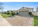 Exterior view of a house with a brick driveway and palm tree at 6364 Domenico Ct, Groveland, FL 34736