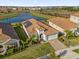 Aerial view of the property with a well-manicured lawn, solar panels, and a view of the lake at 8939 Fallen Oak Dr, Davenport, FL 33896