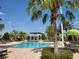 Inviting community pool surrounded by palm trees, lounge chairs, and umbrella-covered seating areas at 8939 Fallen Oak Dr, Davenport, FL 33896