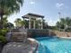Beautiful community pool with a pergola, stone waterfall feature, and lush landscaping at 8939 Fallen Oak Dr, Davenport, FL 33896