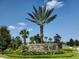 Community entrance sign for 'The Plaza' featuring a palm tree, stone base, and colorful landscaping at 8939 Fallen Oak Dr, Davenport, FL 33896