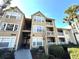 Low-angle exterior view of a tan condo building showcasing multiple stories, balconies, and well-maintained landscaping at 1091 S Hiawassee Rd # 216, Orlando, FL 32835