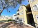 Exterior of the apartment building, featuring yellow siding, a stairway, and grassy surroundings at 1091 S Hiawassee Rd # 216, Orlando, FL 32835