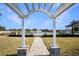 View through a white pergola toward a gazebo on the pond with water feature at 113 Kenny Blvd, Haines City, FL 33844