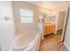 Bright bathroom features a large soaking tub, wood flooring, and oak vanity with vanity lighting at 1145 Sugar Belt Dr, St Cloud, FL 34771