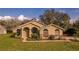 Close-up of a single-story stucco home showcasing arched windows, lush landscaping, and a well-manicured lawn at 1145 Sugar Belt Dr, St Cloud, FL 34771