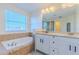 A bright bathroom with tiled shower, soaking tub, dual sink vanity, and a large window at 14637 Tanja King Blvd, Orlando, FL 32828