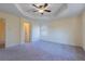 Spacious carpeted bedroom featuring tray ceilings, ceiling fan, and a bright window at 14637 Tanja King Blvd, Orlando, FL 32828