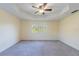 Bright and airy main bedroom features tray ceilings, neutral walls, carpeting, and a large window at 14637 Tanja King Blvd, Orlando, FL 32828