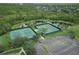 Aerial view of two tennis courts nestled near a pond and surrounded by lush greenery and a parking lot at 14637 Tanja King Blvd, Orlando, FL 32828