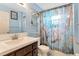 Bathroom with vanity, toilet and shower featuring a floral shower curtain design and a metal shelving unit at 152 Harrison St, Lake Wales, FL 33859